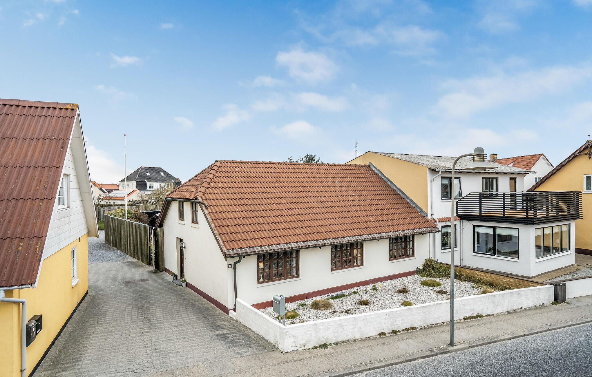 Eine enge Straße mit Häusern, eines mit rotem Ziegeldach und ein anderes mit Balkon.