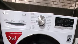 Une machine à laver LG ThinQ blanche, dotée d’une fonction 2-en-1, située dans une pièce carrelée.