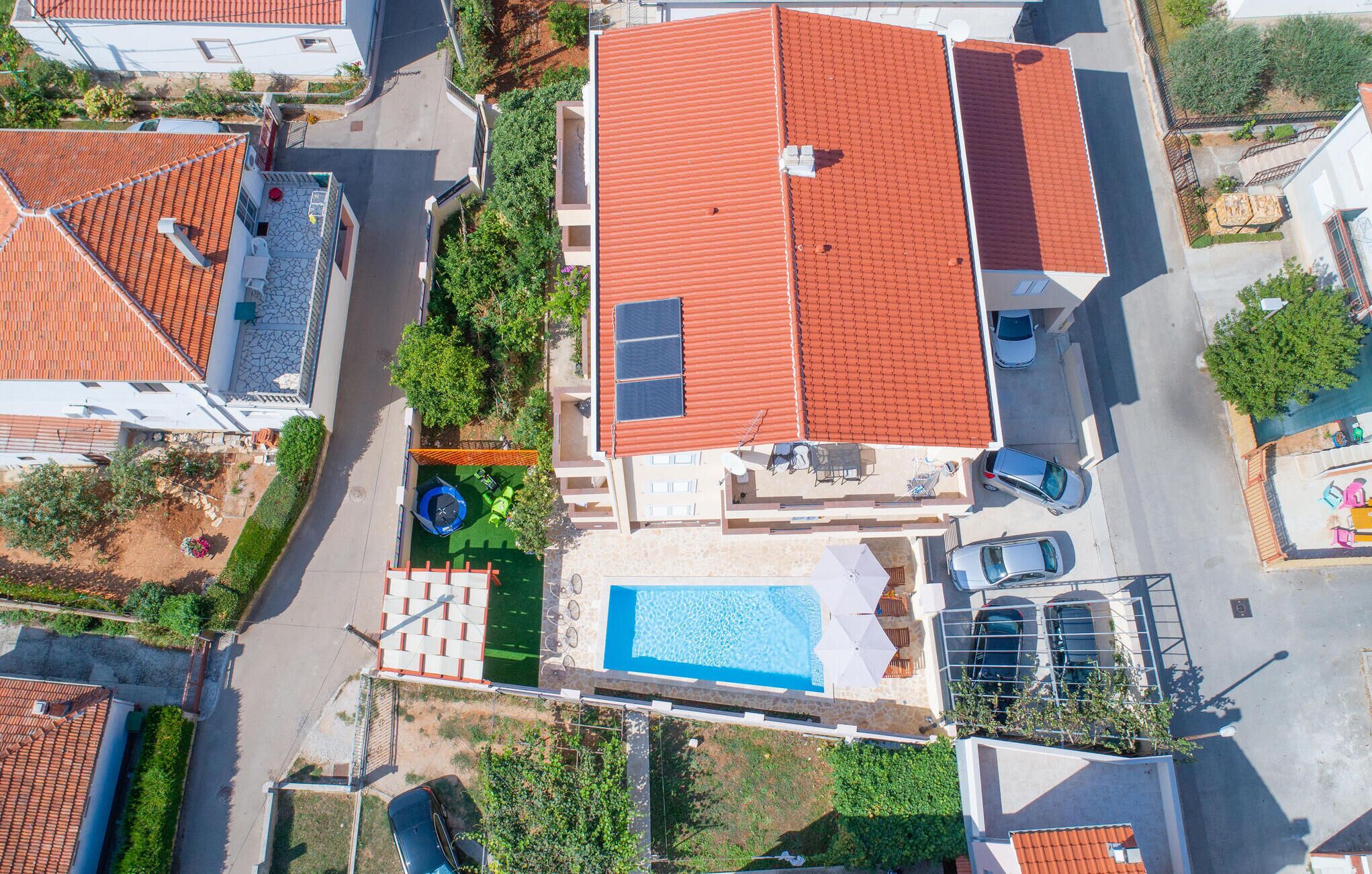 A residential area with multiple houses, a swimming pool, and a street.