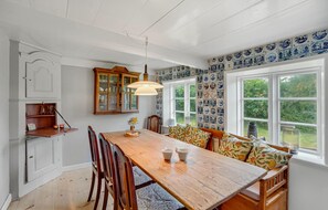 A dining area with a wooden table, chairs, a bench, and a cabinet with glass doors. - 3 bedroom cozy home in Fanø (Fanø)