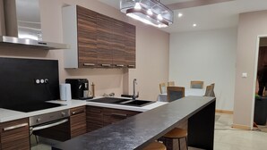 Una cocina moderna con una isla central, electrodomésticos integrados y taburetes de bar.