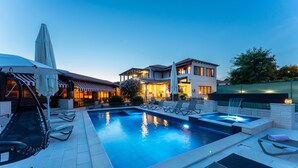 Ein Swimmingpool mit Liegestühlen, einem Whirlpool und einem Restaurant mit Außenbereich.