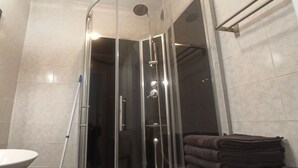 A modern bathroom with a glass-enclosed shower, a white sink, and a stack of towels. - APPRENTICE AMBILLY (Ambilly)