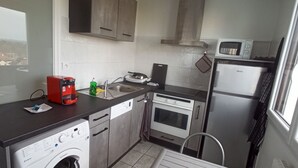 A compact kitchen with a washing machine, a coffee maker, a microwave, and a refrigerator. - APPRENTICE AMBILLY (Ambilly)