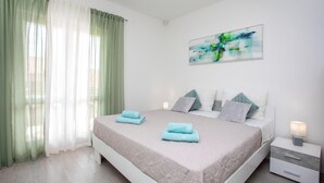 Ein Schlafzimmer mit Bett, Kissen, Nachttisch, Lampe und einem Bild an der Wand.