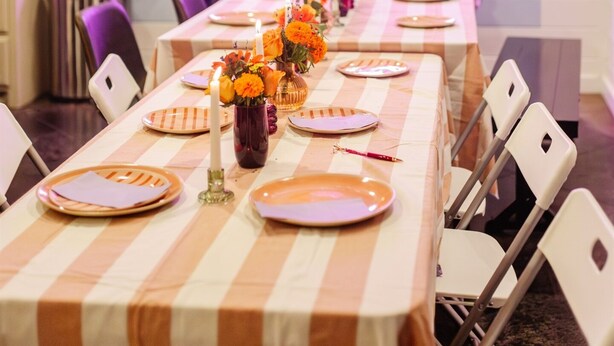 Een eethoek met een lange tafel gedekt voor een maaltijd, omringd door witte stoelen.