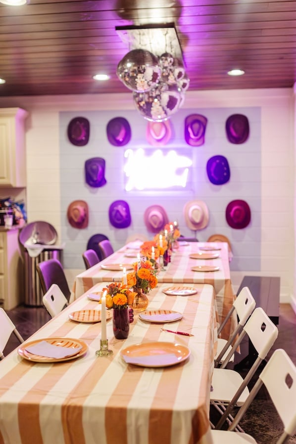 Un espace repas avec une longue table dressée pour le repas, entourée de chaises blanches.