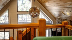 Une pièce avec un plafond en bois, de grandes fenêtres et une boule à facettes suspendue au plafond.