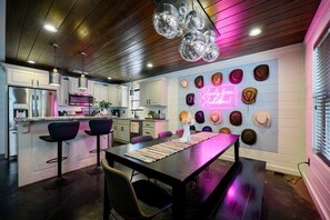 Une cuisine moderne avec un îlot central, des tabourets de bar et un panneau lumineux au néon.