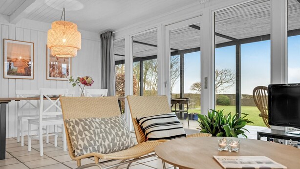 Quarto amplo com área de refeições, um espaço de estar com mesa e cadeiras, e janelas grandes que oferecem vista para o exterior.