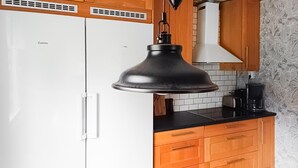 A kitchen with white cabinets, a black pendant light, and a tiled backsplash. - 2 bedroom nice home in Figeholm (Figeholm)