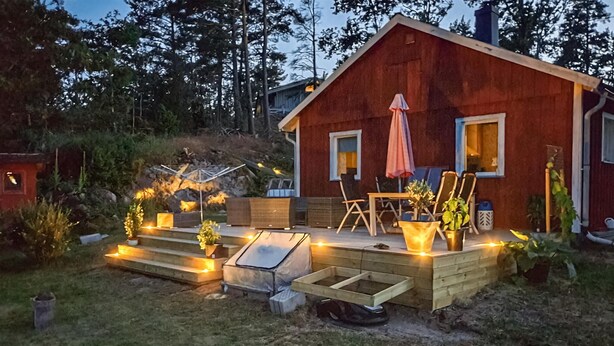 A wooden cabin with a deck, outdoor seating, and a small table. - 2 bedroom nice home in Figeholm (Figeholm)