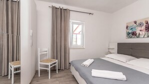 Un dormitorio con cama, una silla, una ventana y un cuadro en la pared.