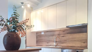 Una cocina moderna con armarios blancos, una encimera de madera, un lavamanos de acero inoxidable y un horno.