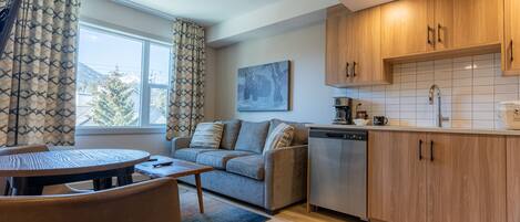 A modern kitchen with wooden cabinets, a dishwasher, and a window with curtains.
