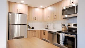 A modern kitchen with wooden cabinets, stainless steel appliances, and a dining area with a table and chairs.