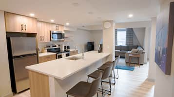 A modern kitchen with a large island, stainless steel appliances, and a dining area with bar stools.