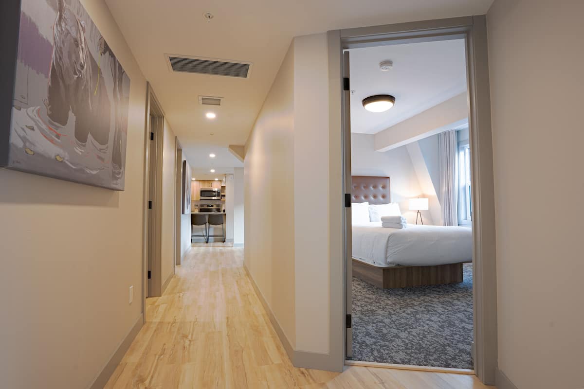 En hotellkorridor som leder till ett sovrum med en säng, ett skrivbord och en stol.