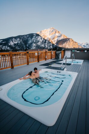 A hot tub on a wooden deck with a mountain view in the background. - Basecamp Suites Banff (Banff)