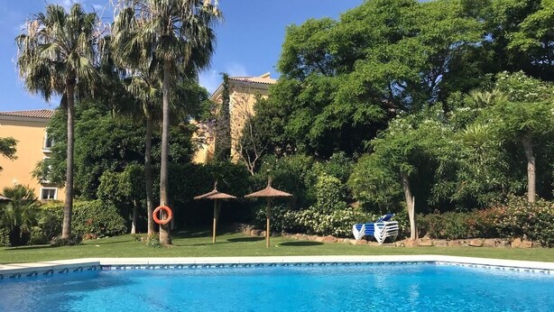 Ein Schwimmbad mit Palmen und einem Gebäude im Hintergrund.