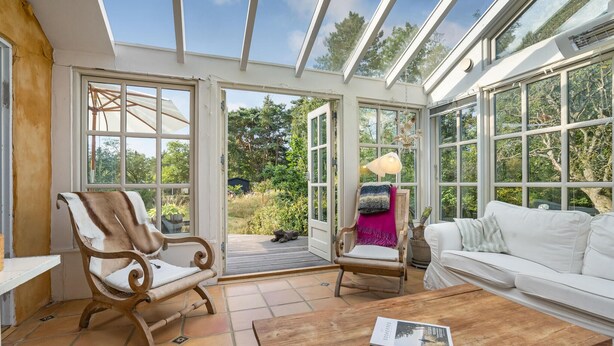 A conservatory with a wooden chair, a white sofa, and a wooden table. - Cozy home in Højby with kitchen (Højby)