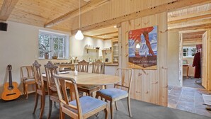 Un intérieur en bois avec une table à manger, des chaises, une guitare et une affiche.