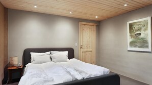 Une chambre à coucher avec un lit, une porte en bois et un tableau accroché au mur.