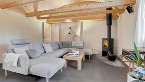 Un salon chaleureux avec un canapé d’angle, une table basse, une cheminée et un plafond en bois.