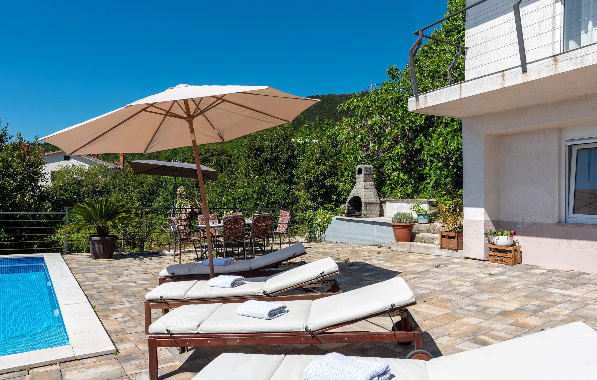 A poolside area with lounge chairs, a table, and an umbrella.