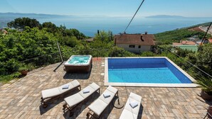 Una piscina en la azotea con sillones, un jacuzzi y vista al mar.