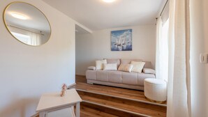 Una sala de estar moderna con un sofá, un espejo redondo, un cuadro y una mesita.