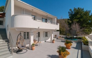 A two-story building with a balcony, outdoor seating, and potted plants. - Awesome home in Zrnovnica (Zrnovnica)