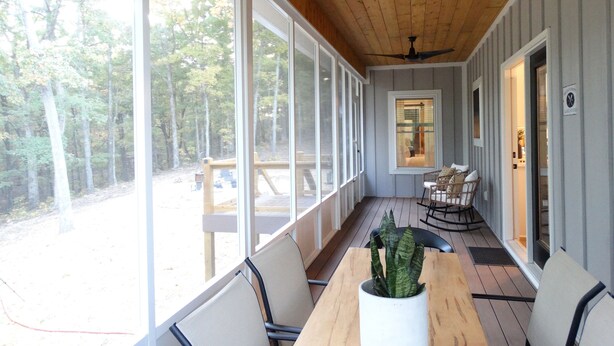 A covered patio with a wooden ceiling, large windows, and a table with chairs. - Beautiful new home at Kentucky Lake with community pool! Close to Murray State! (Murray)