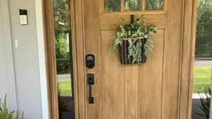 A wooden double door with a black doormat, a potted plant, and a keypad lock. - Beautiful new home at Kentucky Lake with community pool! Close to Murray State! (Murray)