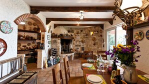 A rustic dining area with a stone fireplace, wooden beams, and a variety of kitchen utensils and decorations. - Nice home in Kostrena (Kostrena)