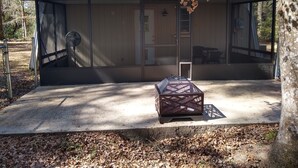 Un edificio moderno con un amplio portón de vidrio corredera, un pequeño porche cerrado y una parrilla metálica en el suelo.