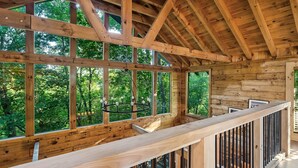 Eine Holzhütte mit großen Fenstern, einer Holzdachterrasse und einer hängenden Leuchte.