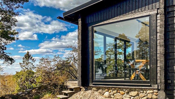 Un bâtiment moderne doté d’une grande fenêtre en verre qui reflète les arbres et le ciel.