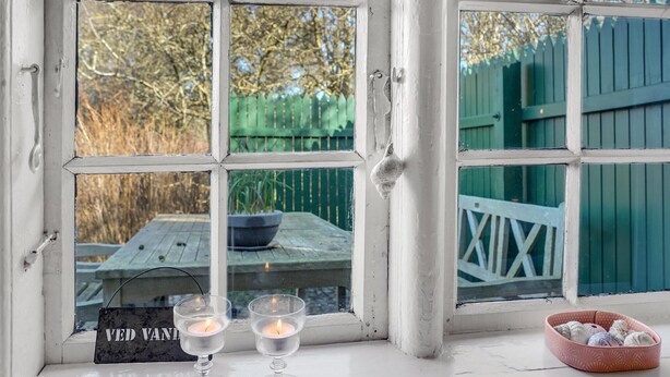 A window with a view of a wooden deck and a green fence.