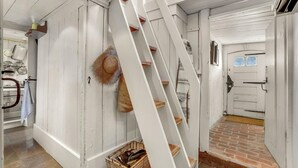 A white interior with a staircase, a door, and a brick floor.