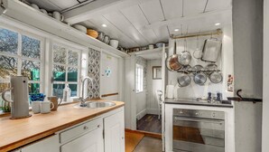 A kitchen with white cabinets, a wooden countertop, a stainless steel sink, and a built-in oven.