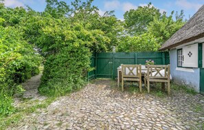 Relax in a serene outdoor setting surrounded by lush greenery and a traditional building with a thatched roof.
