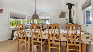 Ein Essbereich mit einem für vier Personen gedeckten Tisch, umgeben von Holzsesseln, beleuchtet von zwei Pendelleuchten.