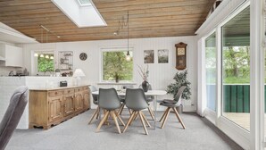 A modern kitchen with white cabinetry, a wooden ceiling, and a dining area with grey chairs and a white table. - Amazing home in Brovst with kitchen (Brovst)