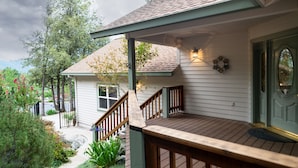 Een huis met een houten terras, een voortuin en een voordeur met een decoratief glasraam.