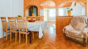 A dining area with wooden chairs and a table, a cozy armchair, and a potted plant.