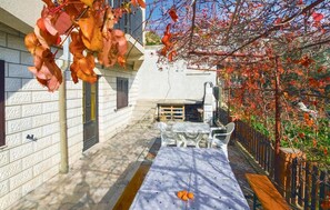 Eine Terrasse mit Tisch und Stühlen, einer hölzernen Bank und einer Ziegelwand.