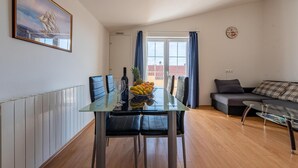 A modern living room with a glass dining table, black leather chairs, a sofa, and a coffee table. There is a painting on the wall and a clock. - Cozy apartment in Zadar with WiFi (Zadar)