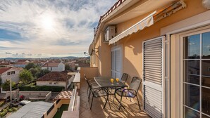 A balcony with a table and chairs, a view of the city, and a building with a beige facade. - Cozy apartment in Zadar with WiFi (Zadar)