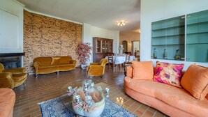 A living room with a fireplace, a dining area, and a kitchen visible in the background. - Nice home in Asti with jacuzzi (Asti)